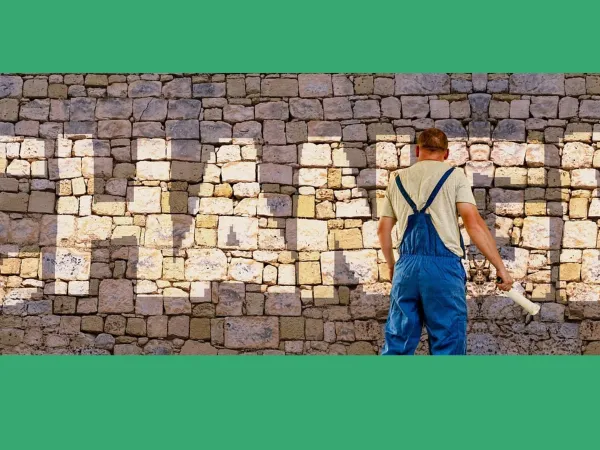 Mann im blauen Overall vor Steinwand, auf der in beige-farbenen Buchstaben "Change" steht